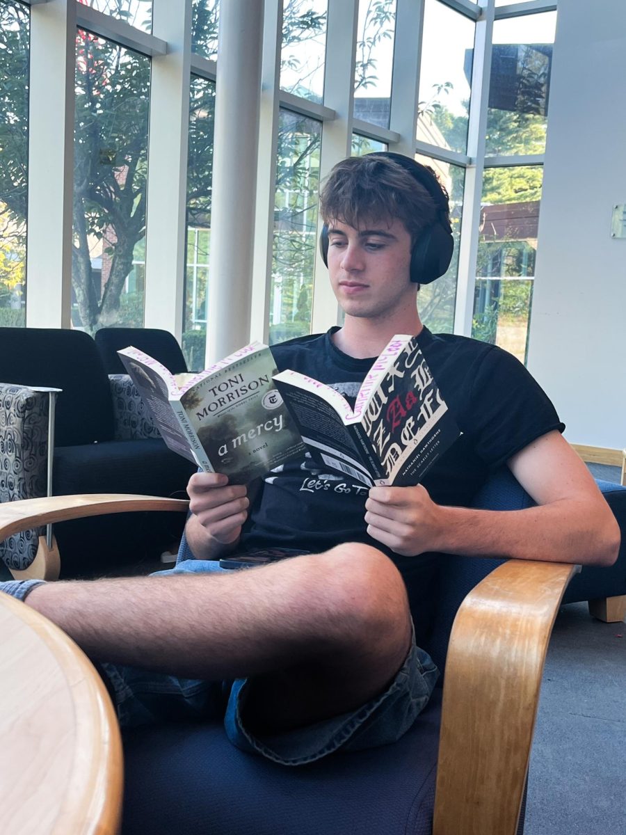 Christian Eckford (Class III) reading feminist literature in jorts with headphones on
